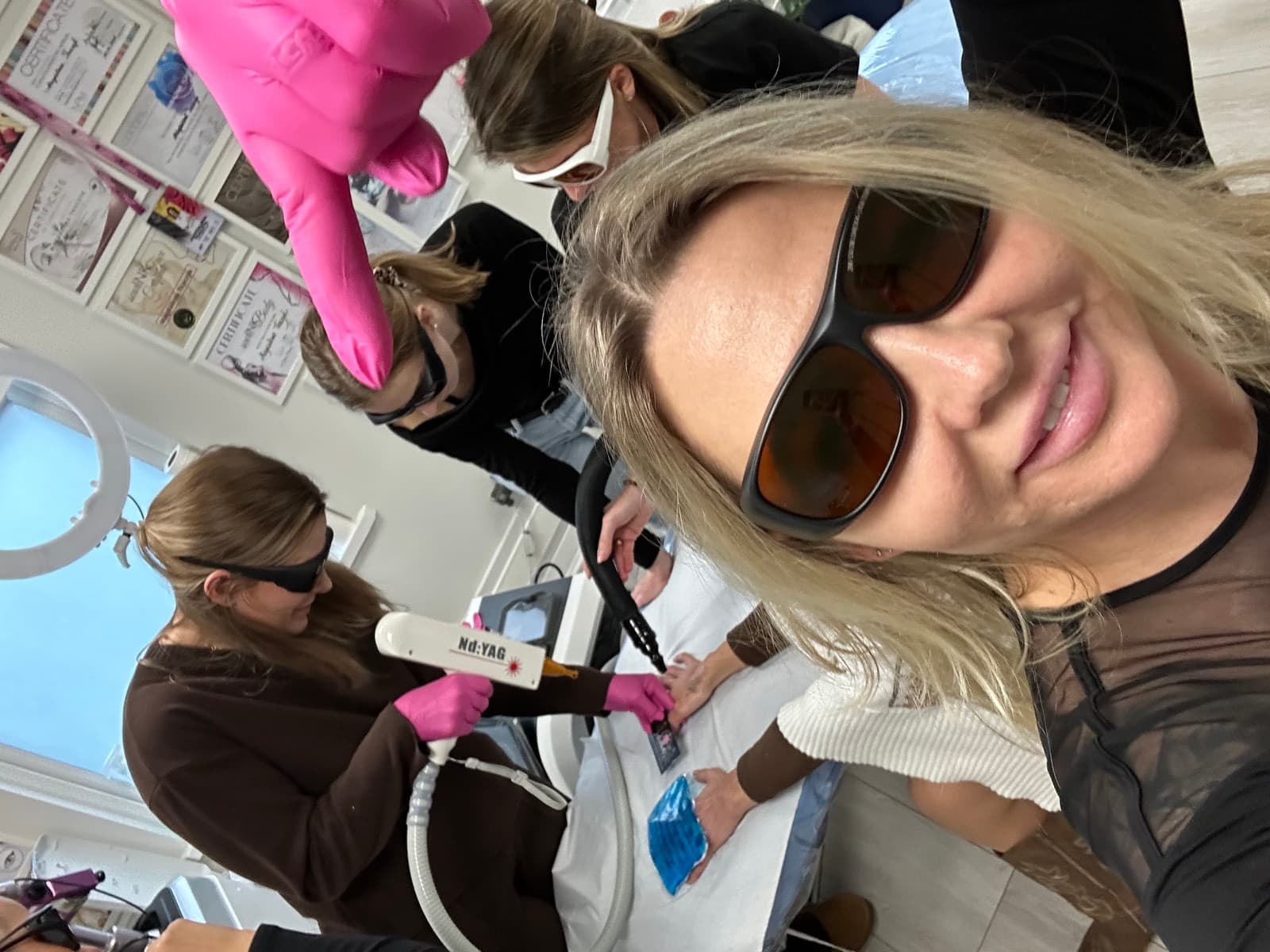 Selfie trenerki podczas szkolenia, w tle kursantka pracuje głowicą lasera